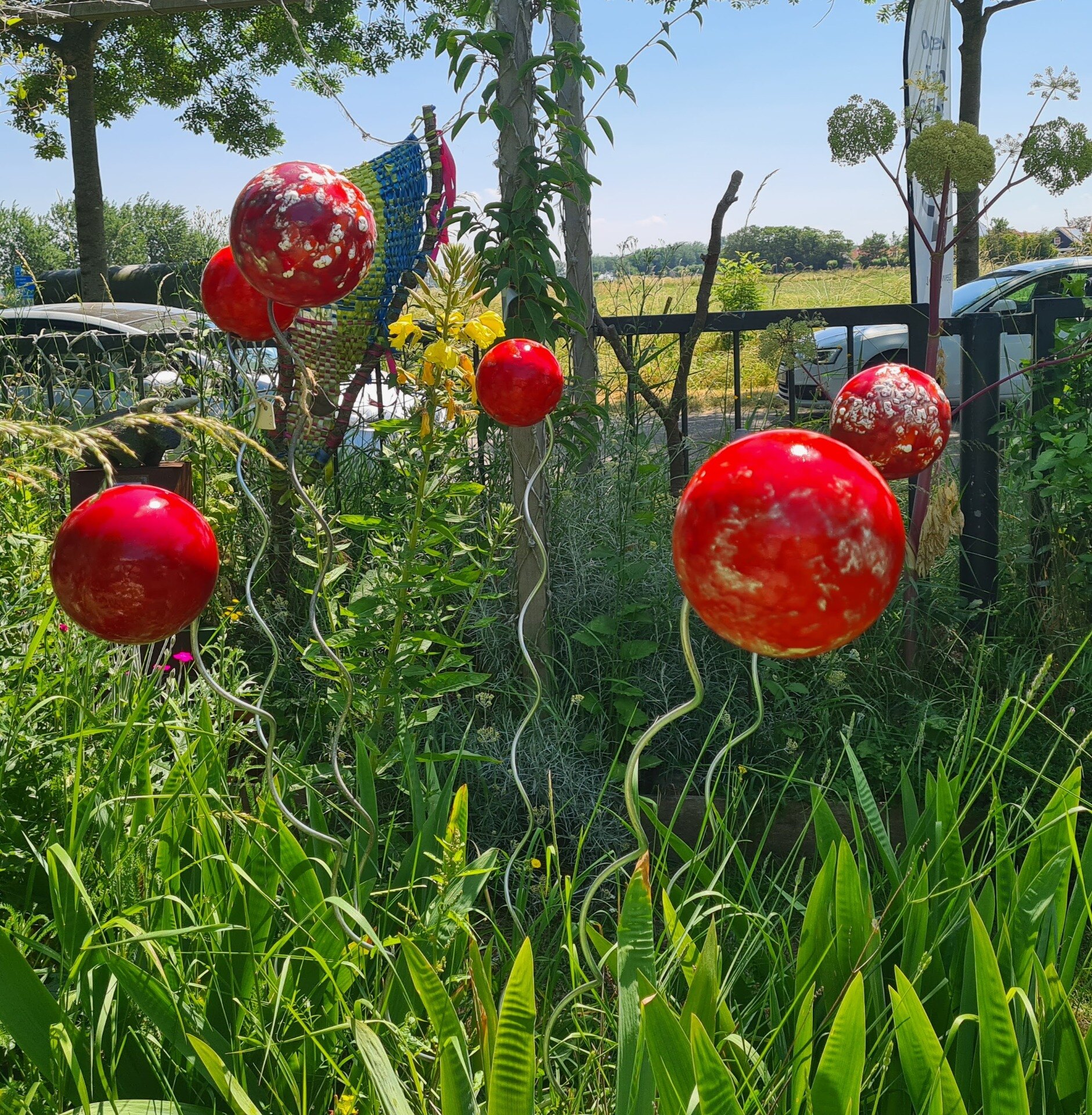 Rode tuinballen tussen het groen van de galerietuin